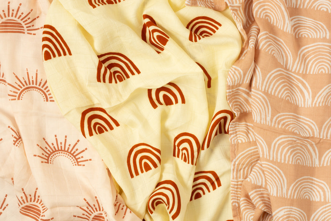 Close-up of sun and rainbow bamboo muslin cloths draped to show the print and soft gauze texture
